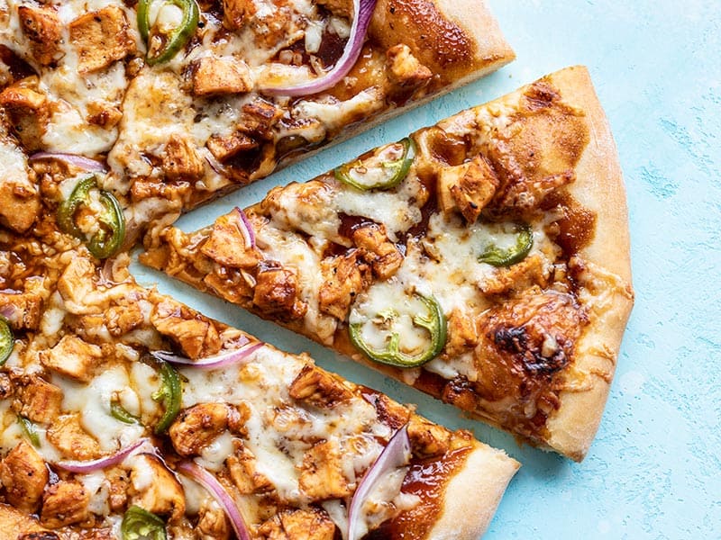 Close up of one slice of BBQ Chicken Pizza being pulled away from the pie