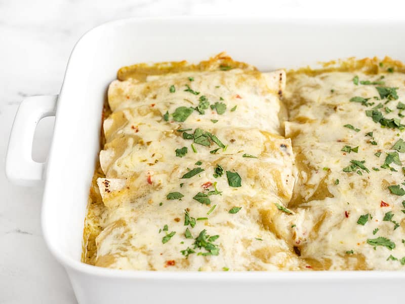 Side view of the casserole dish full of green chile chicken enchiladas