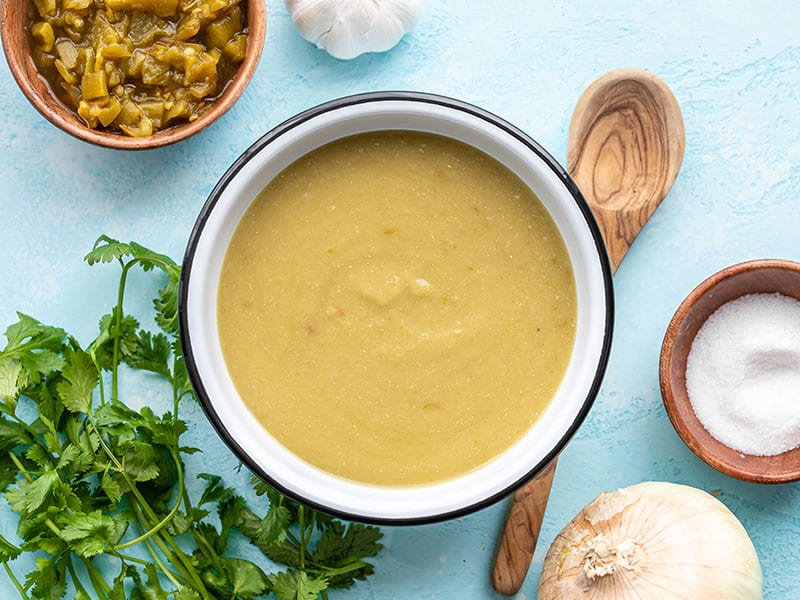 Finished green chile enchilada sauce in a bowl with a wooden spoon on the side