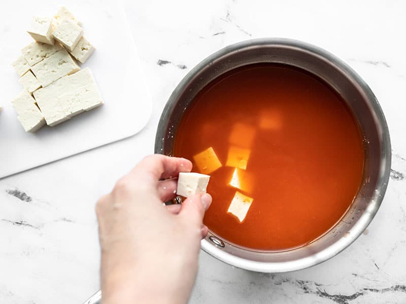 Cubed tofu being dropped into the pot