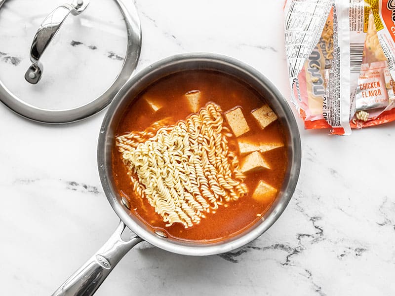 Ramen noodles added to the pot, empty package on the side