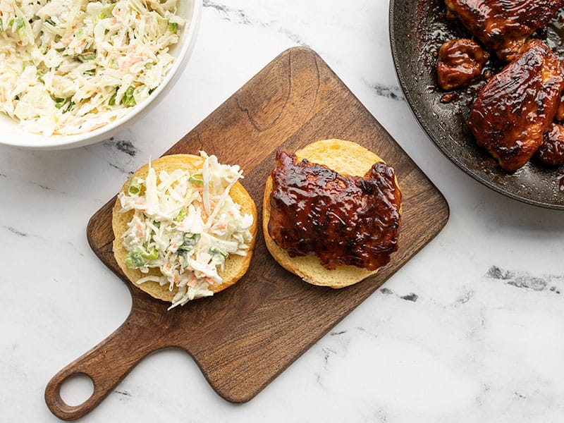 BBQ chicken sandwich being built on a wooden cutting board