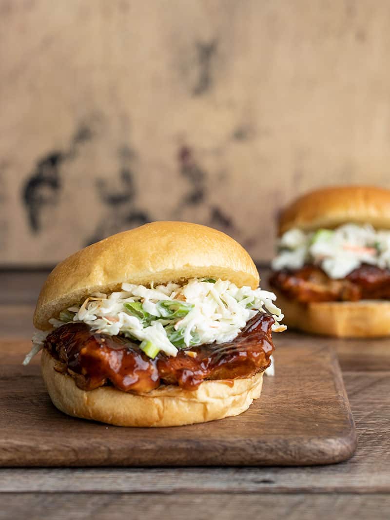 Two Easy BBQ Chicken Sandwiches, one on a wooden cutting board