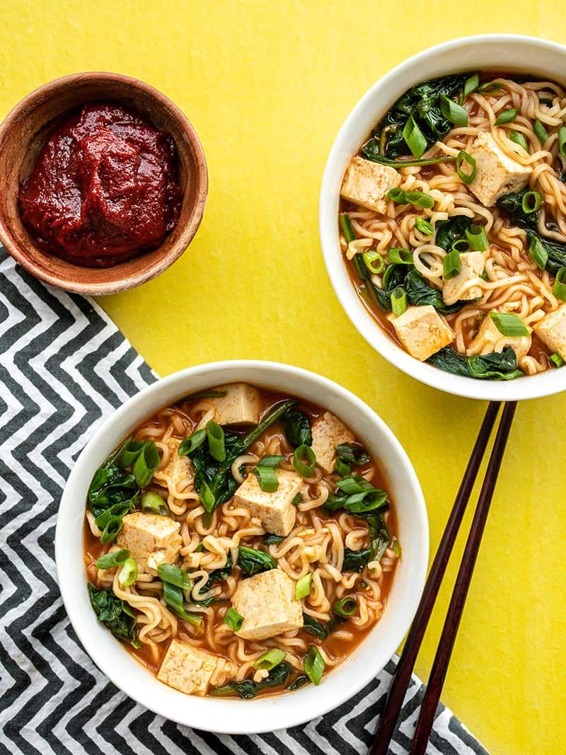 Two bowls of gochujang ramen with tofu, a bowl of gochujang on the side