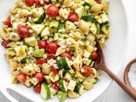 Close up of a bowl of Summer Sweet Corn Salad with a wooden spoon in the middle