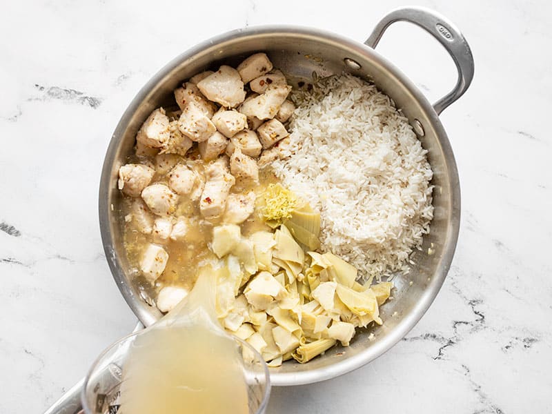 Artichokes, rice, and broth added to the skillet