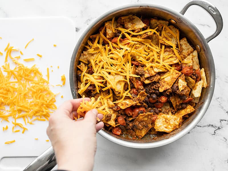 Shredded cheese being added to the skillet