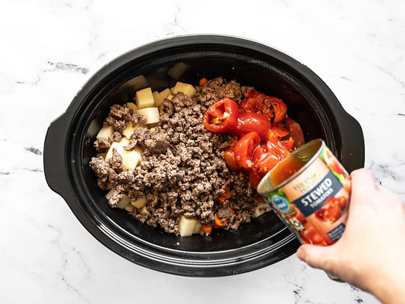 Browned ground beef and stewed tomatoes added to slow cooker