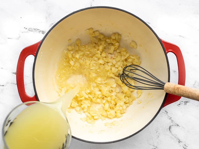 Chicken broth being whisked into the pot