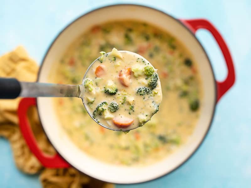 Close up of a ladle full of broccoli cheddar soup