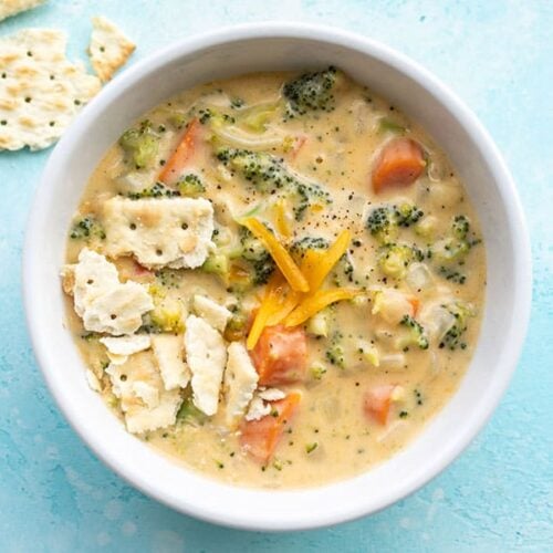 Overhead view of a bowl of broccoli cheddar soup with saltine crackers