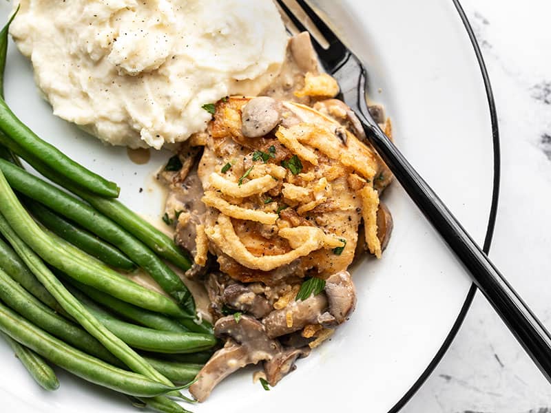 Creamy mushroom chicken on a plate with mashed potatoes and green beans