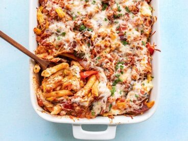 Overhead view of roasted vegetable baked penne being scooped out of the casserole dish