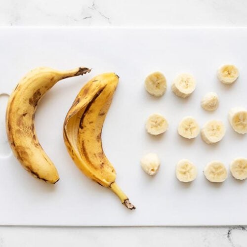 A close-up of freshly sliced bananas arranged neatly on a wooden cutting board.