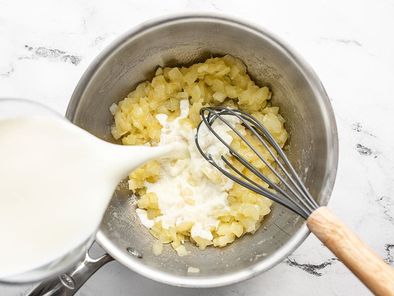 milk being poured into sauce pot