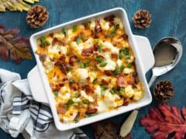 Overhead view of cheesy loaded cauliflower casserole on a blue background