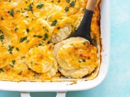 Close up overhead view of potatoes au gratin being scooped out of the casserole dish.