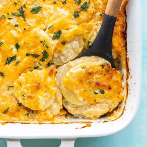 Close up overhead view of potatoes au gratin being scooped out of the casserole dish.