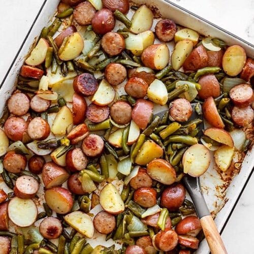 Sheet pan roasted kielbasa potatoes and green beans with a spatula