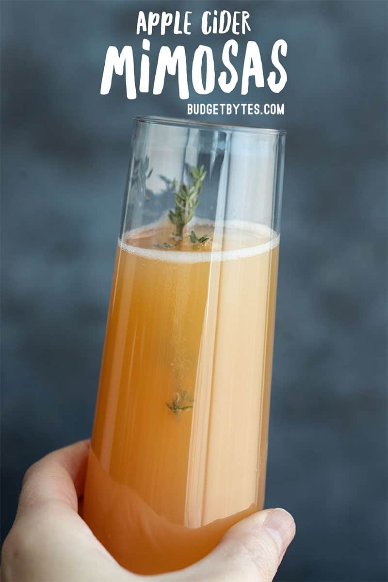 one apple cider mimosa held close to the camera with title text at the top