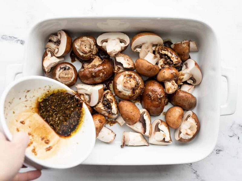 Marinade being poured over the mushrooms in the dish.