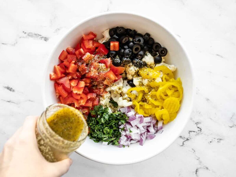 Italian dressing being poured over salad ingredients.