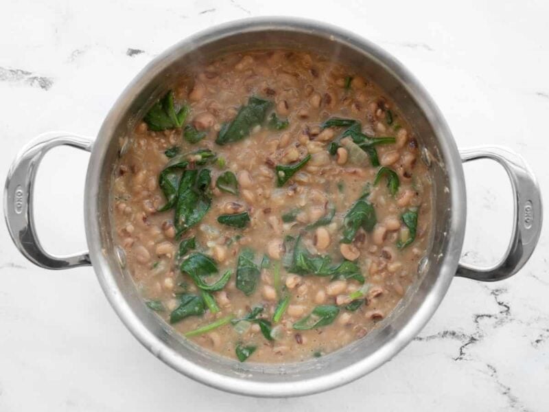 Spinach wilted into the peas in the pot