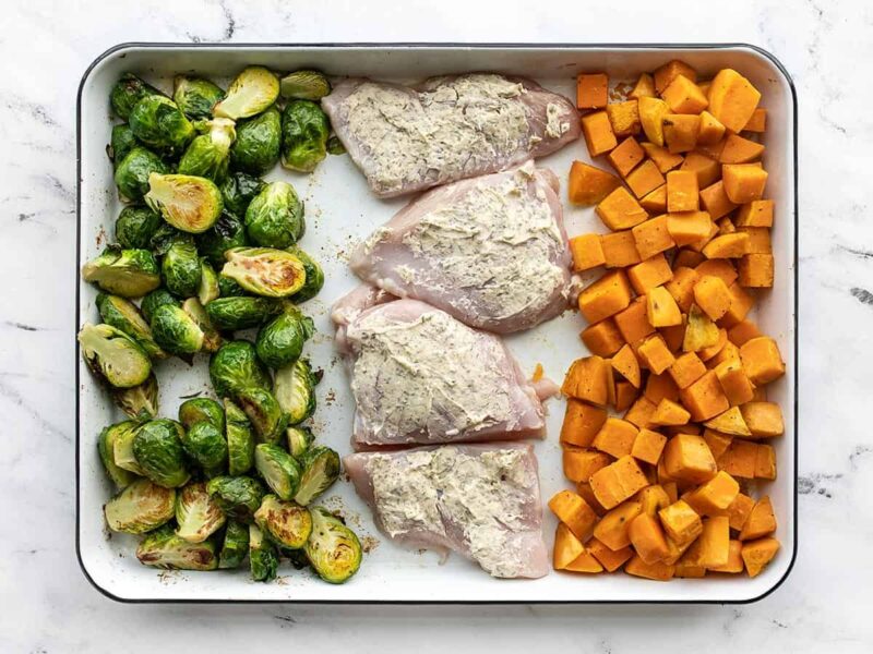 Chicken added to the baking sheet with the roasted vegetables