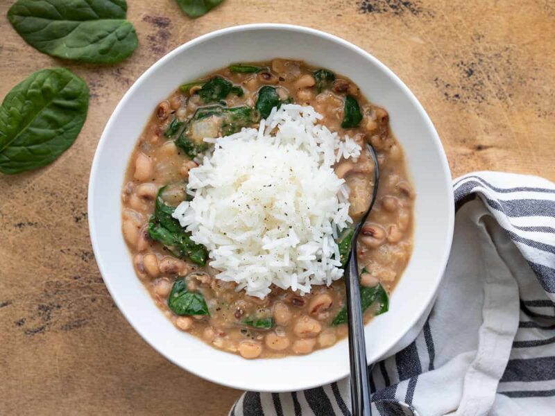 Overhead view of a bowl of black eyed peas and greens with rice in the center