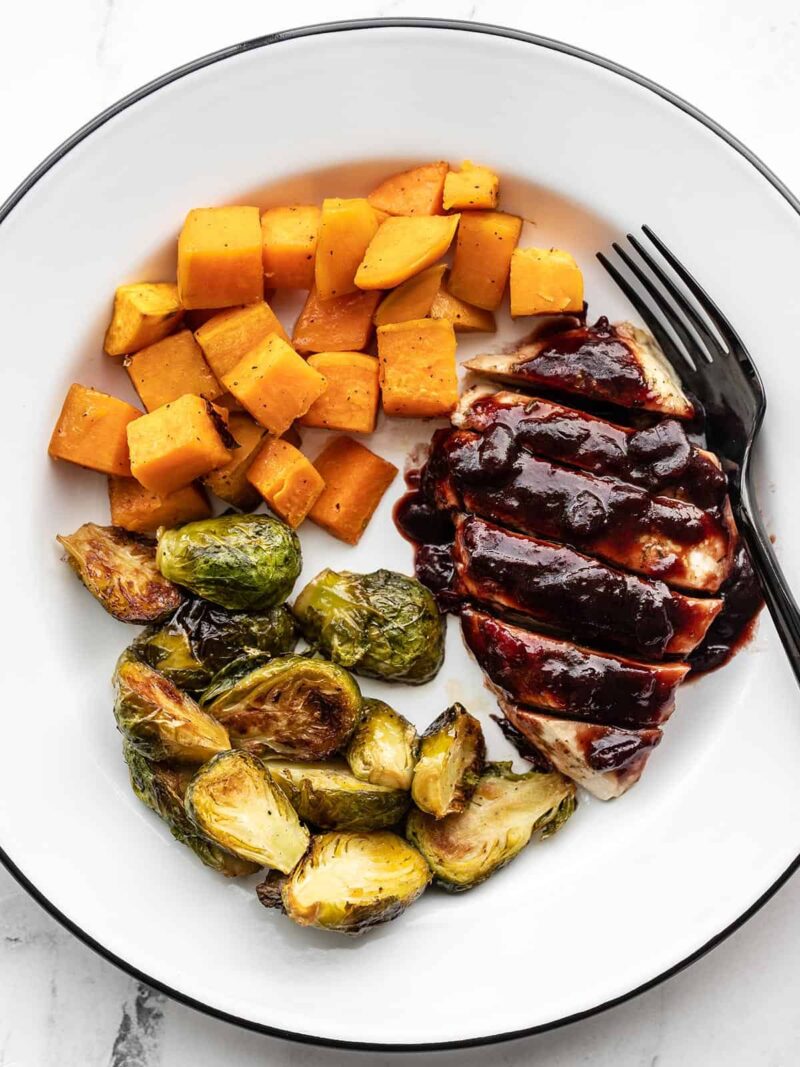 Cranberry chicken on a plate with roasted Brussels sprouts and sweet potatoes