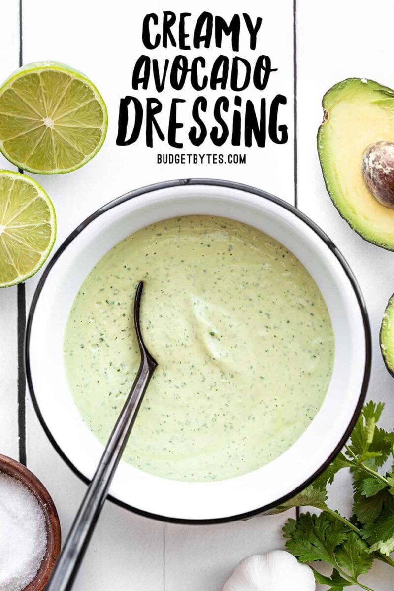 Creamy avocado dressing in a bowl with a black spoon, title text at the top