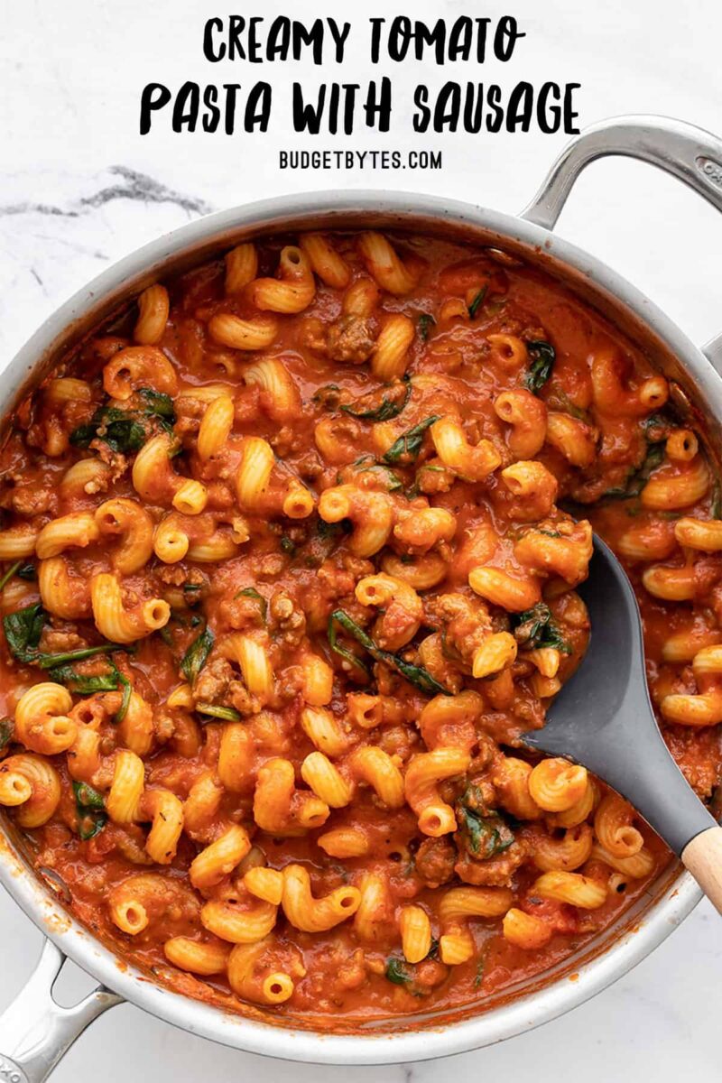 Overhead of creamy tomato pasta with sausage, title text at the top