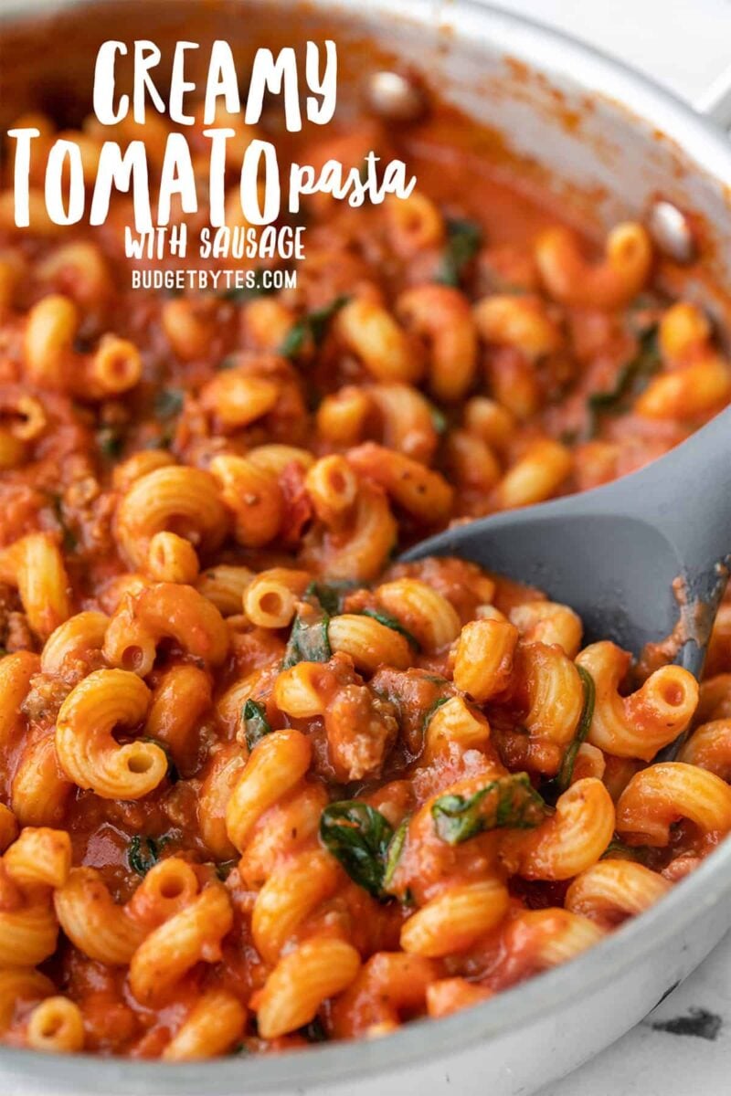 Close up side view of creamy tomato pasta with sausage, title text at the top