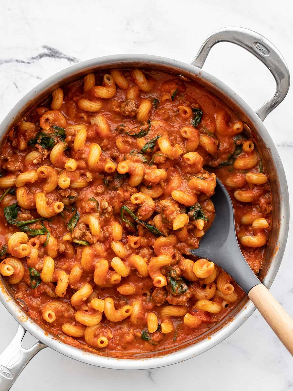 Overhead view of a pan full of Creamy Tomato Pasta with Sausage with a spoon in the side