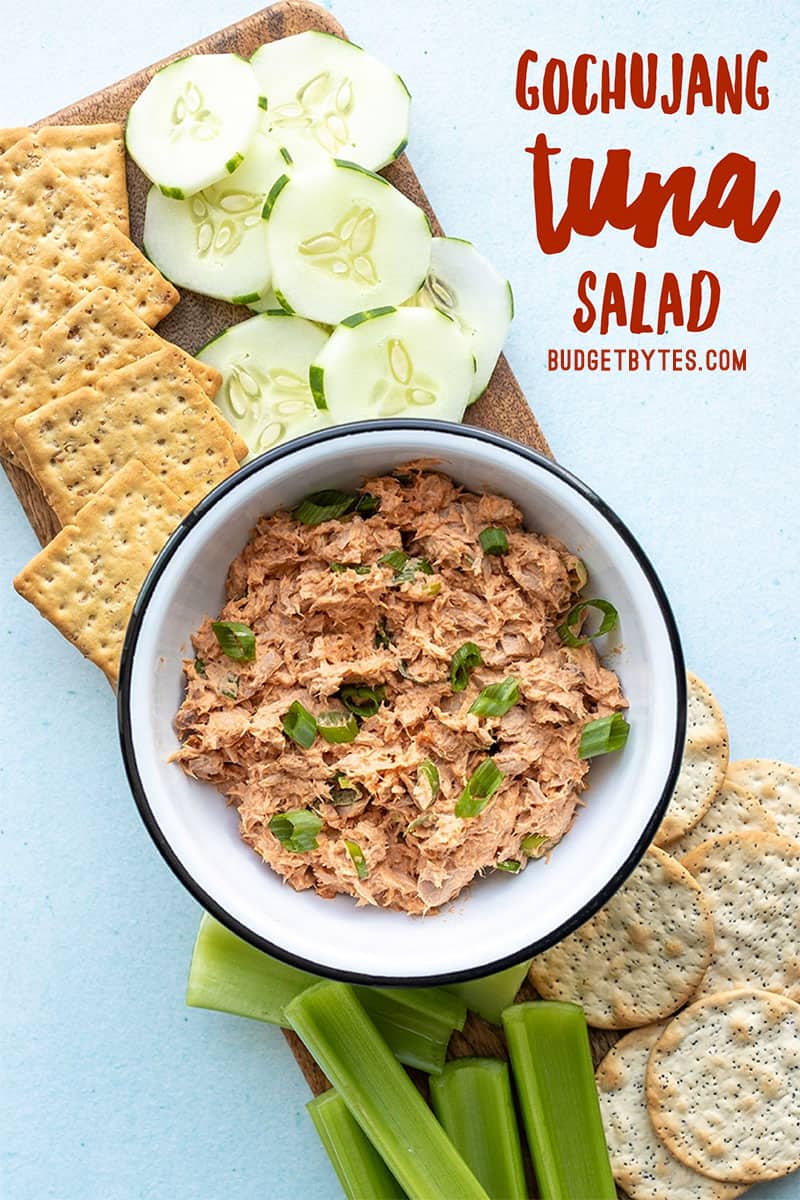 a bowl of gochujang tuna salad surrounded by vegetables and crackers