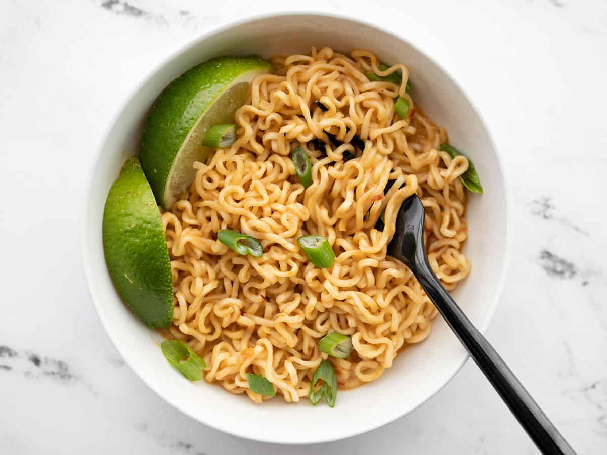 Overhead view of a bowl of spicy peanut butter ramen with a fork in the middle