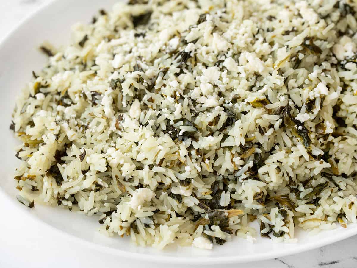 Close up side view of spinach rice with feta on a serving dish