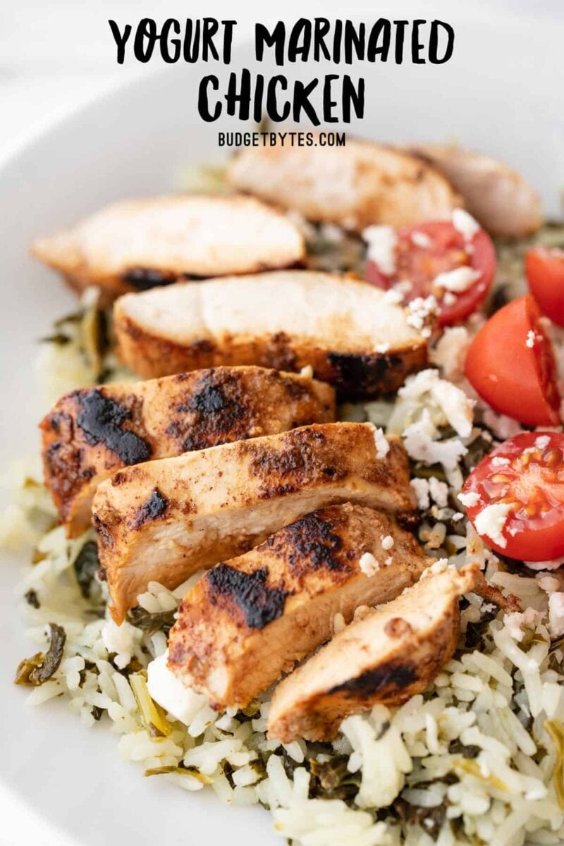 Sliced yogurt marinated chicken on a bed of rice with tomatoes