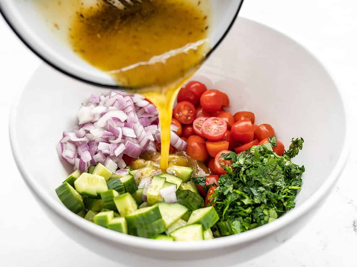 Vinaigrette being poured over vegetables in the bowl