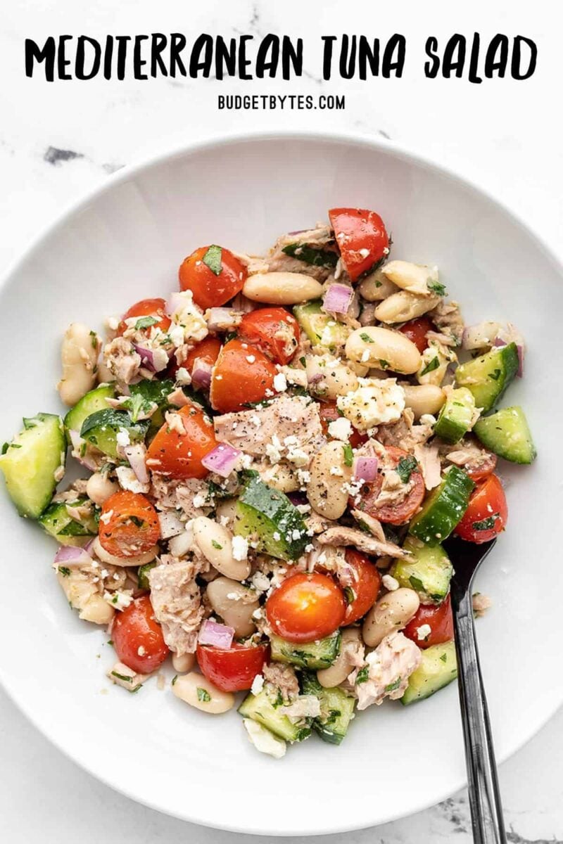 Overhead view of mediterranean tuna salad in a bowl with a fork, title text at the top