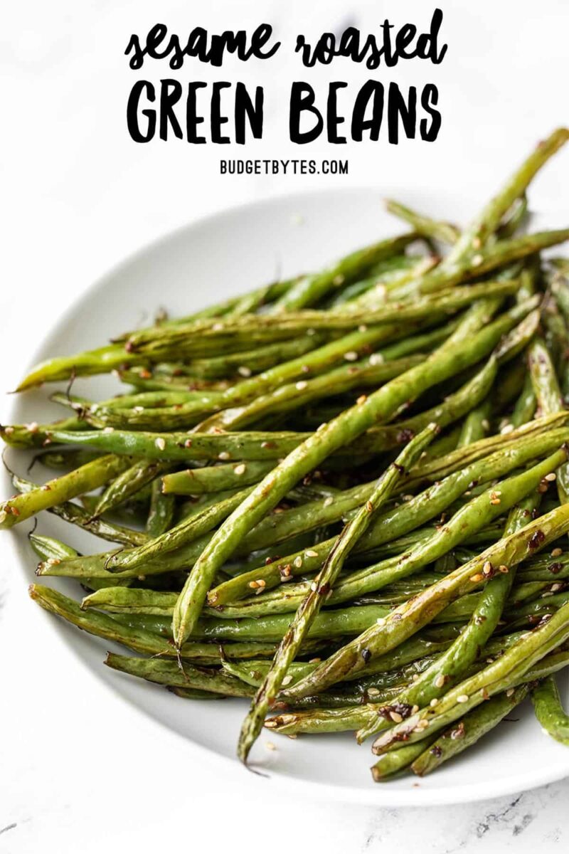 Side view of sesame roasted green beans in a bowl, title text at the top