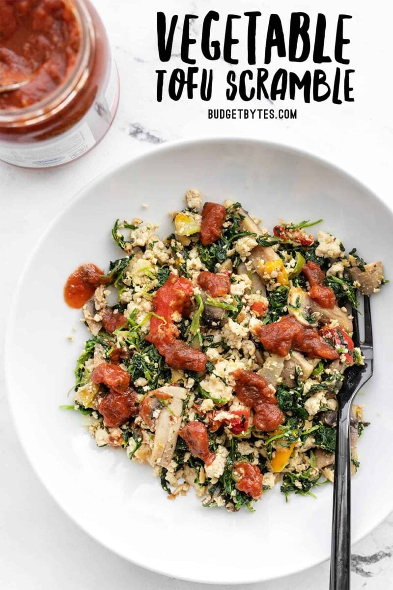 Vegetable Tofu Scramble in a bowl, topped with salsa, jar of salsa on the side