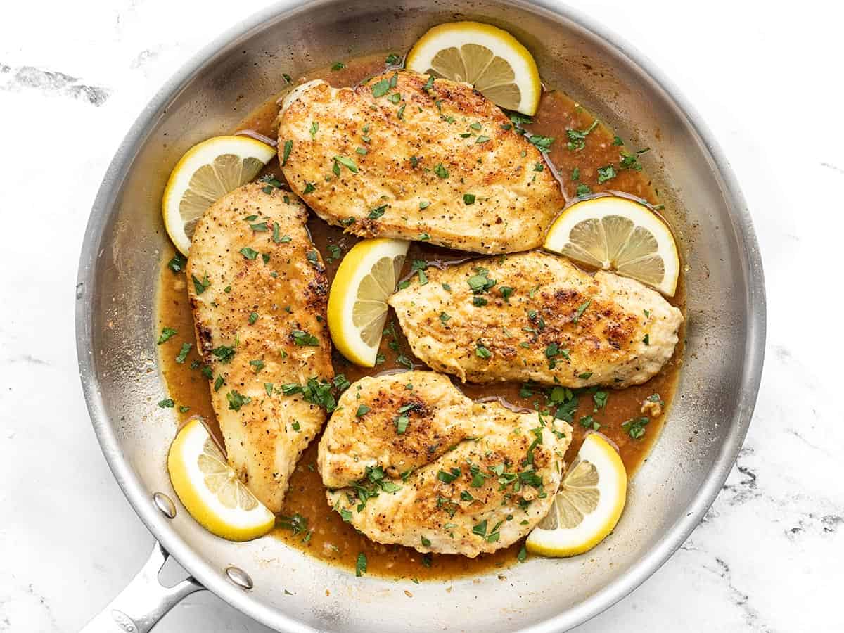 Overhead view of lemon pepper chicken in the skillet with lemon slices