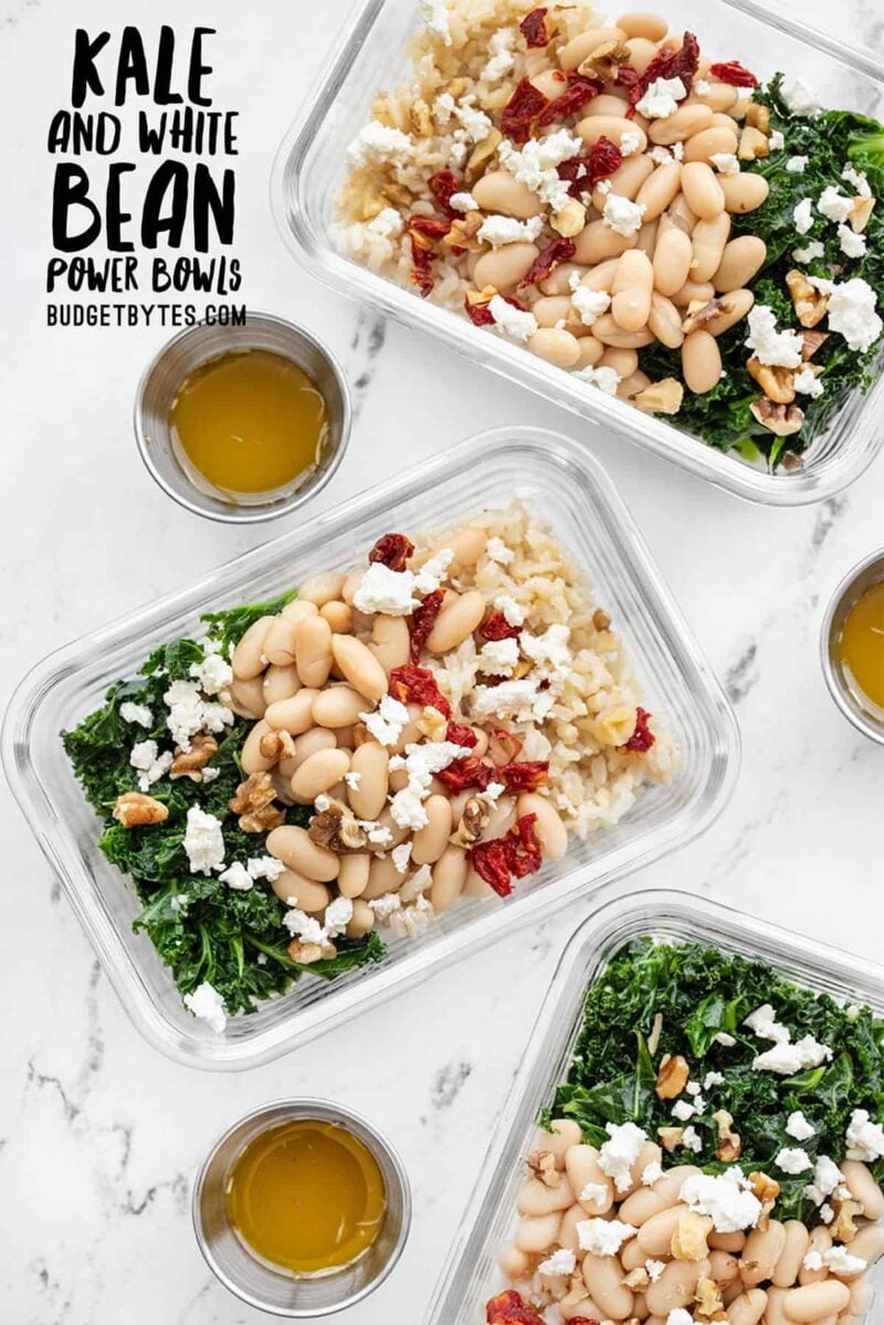 Three glass meal prep containers filled with kale and white bean power bowls