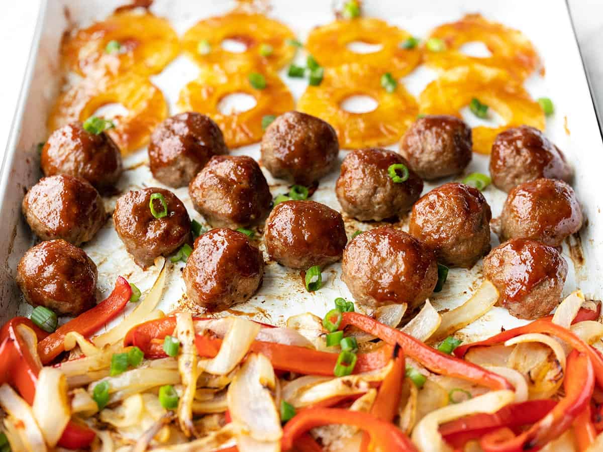 Side view of sheet pan with peppers and onions, bbq meatballs, and pineapple slices