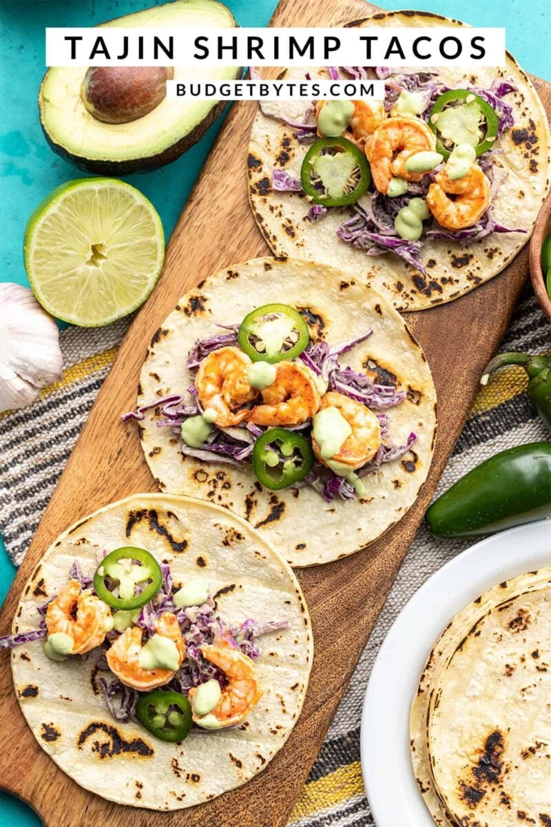 Three open faced Tajín Shrimp Tacos on a wooden board, title text at the top