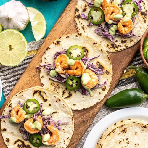 Three Tajín Shrimp Tacos open faced on a wooden board