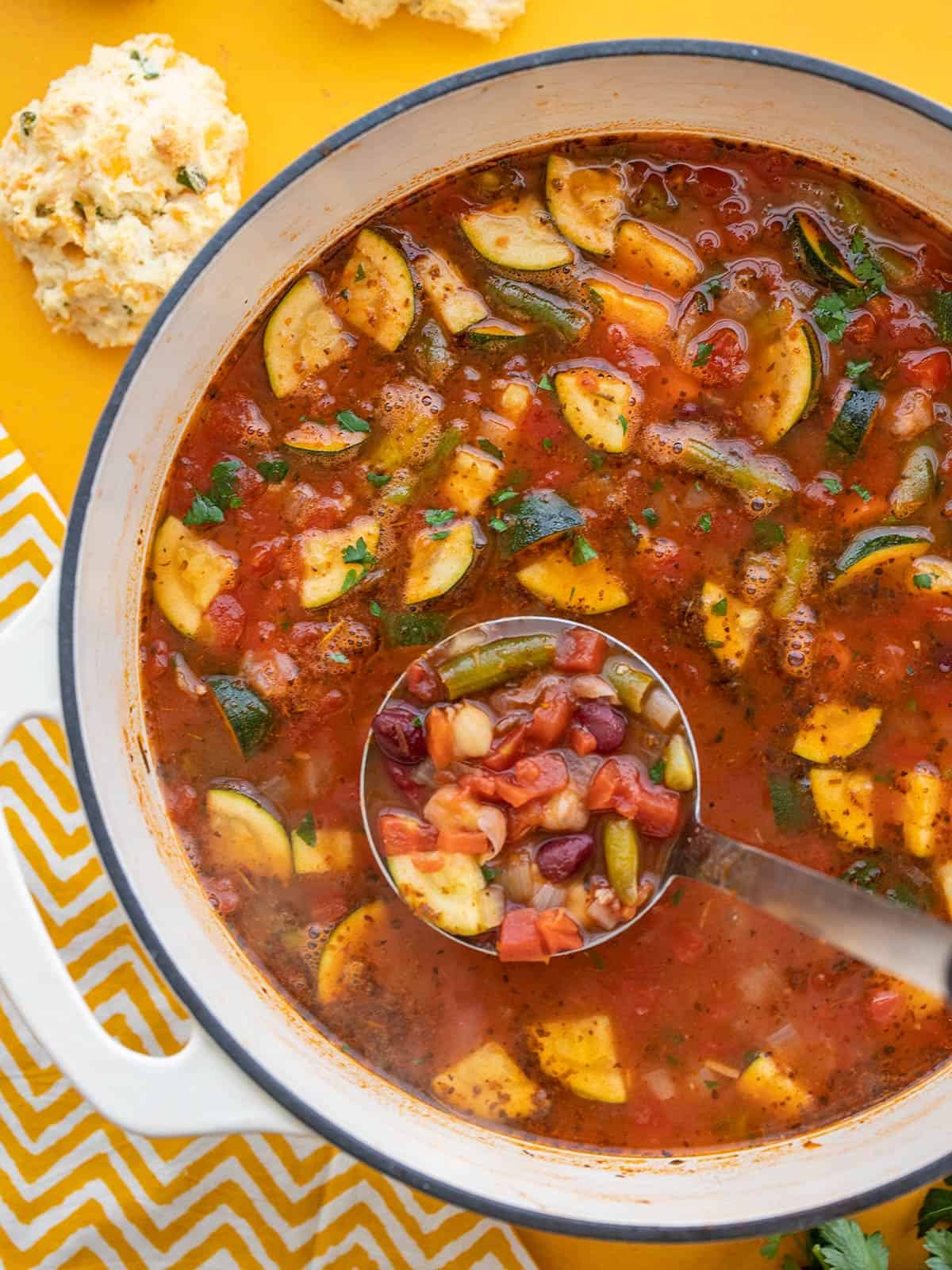 Close up overhead shot of vegetarian minestrone in the pot with a ladle