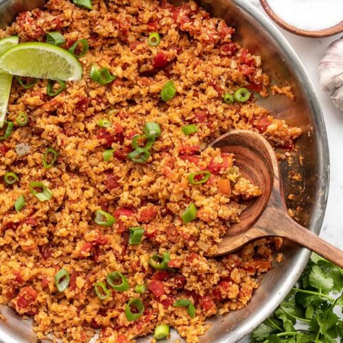 Close up overhead of southwest cauliflower rice in a skillet with a wooden spoon