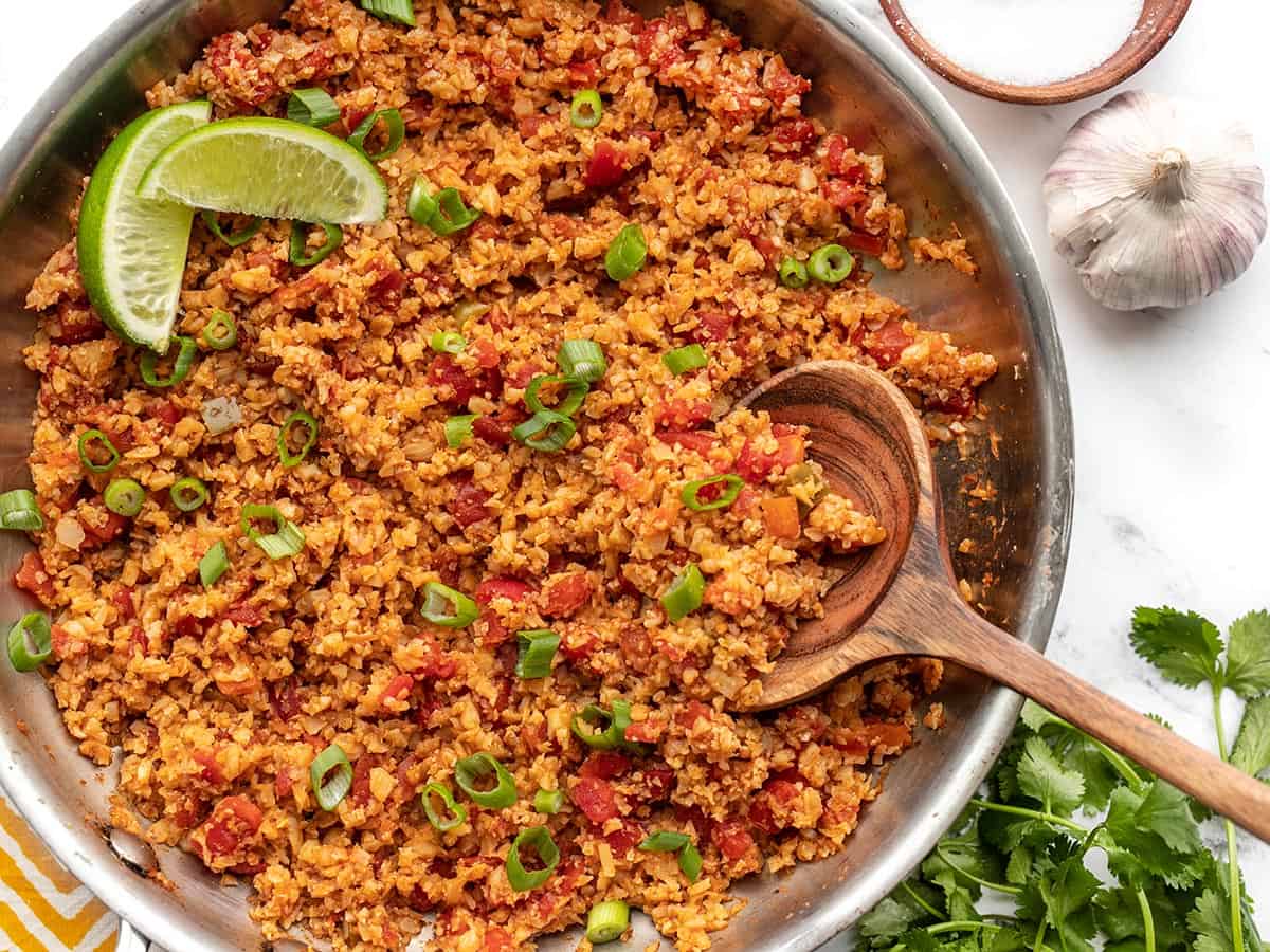 Close up overhead of southwest cauliflower rice in a skillet with a wooden spoon